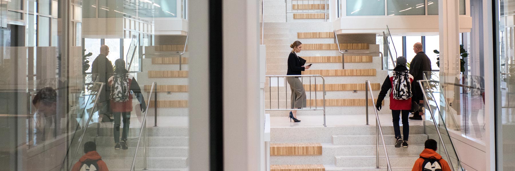 An attractive picture of people walking through a building with mirrored walls, creating a M.C. Escher visual effect.