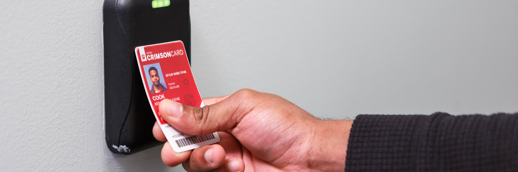 A young man swipes his Crimson Card to enter one of IUPUI's buildings.