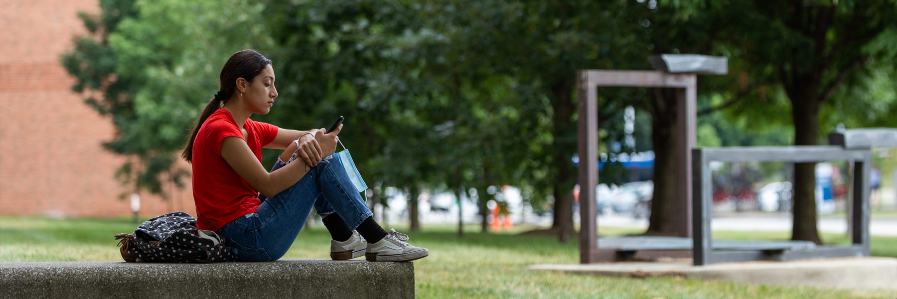 A female IUPUI student checks her phone on a warm summer's day.