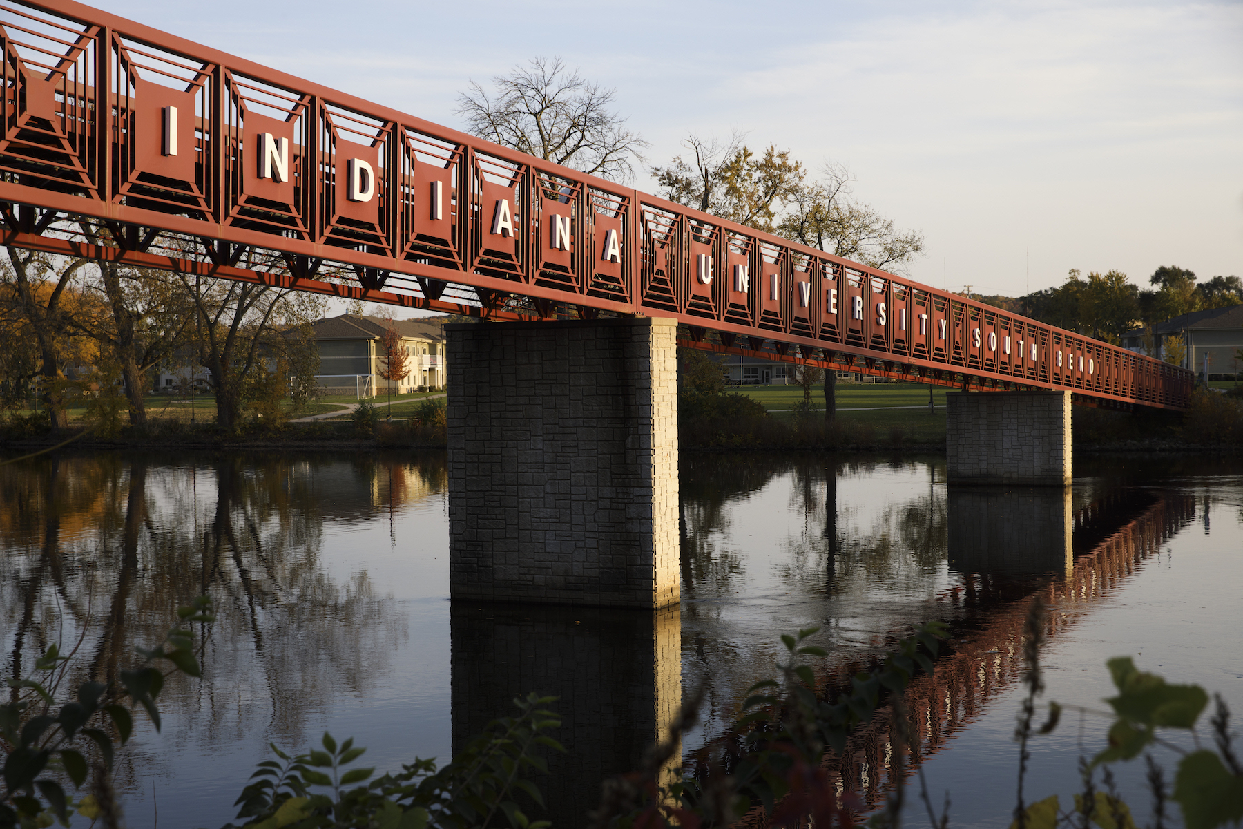 A red bridge over water with the words "Indiana University South Bend" in white
