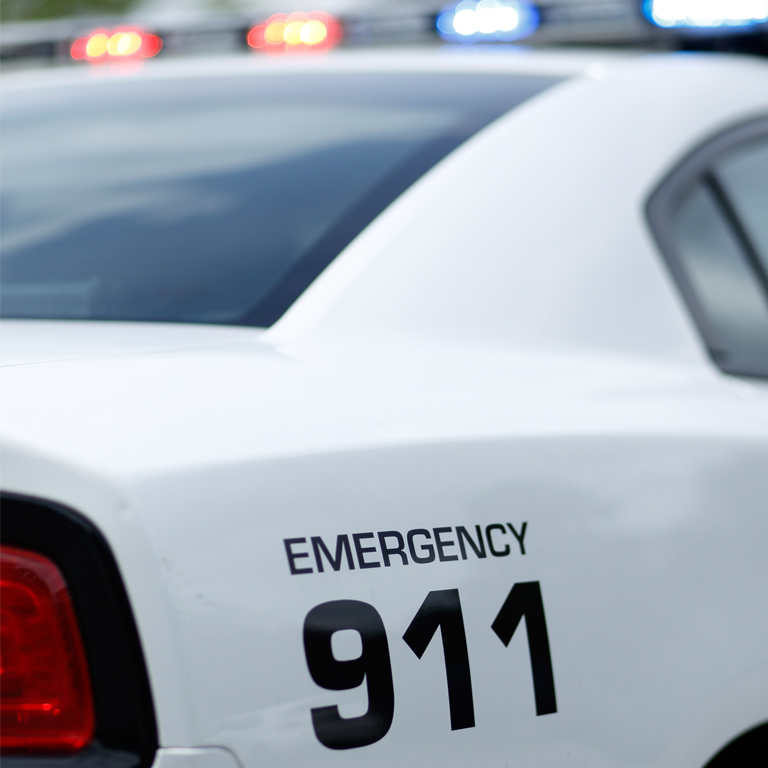 A shallow-focus photo of the side of an IUPD car, with the 911 numbers in closest focus.