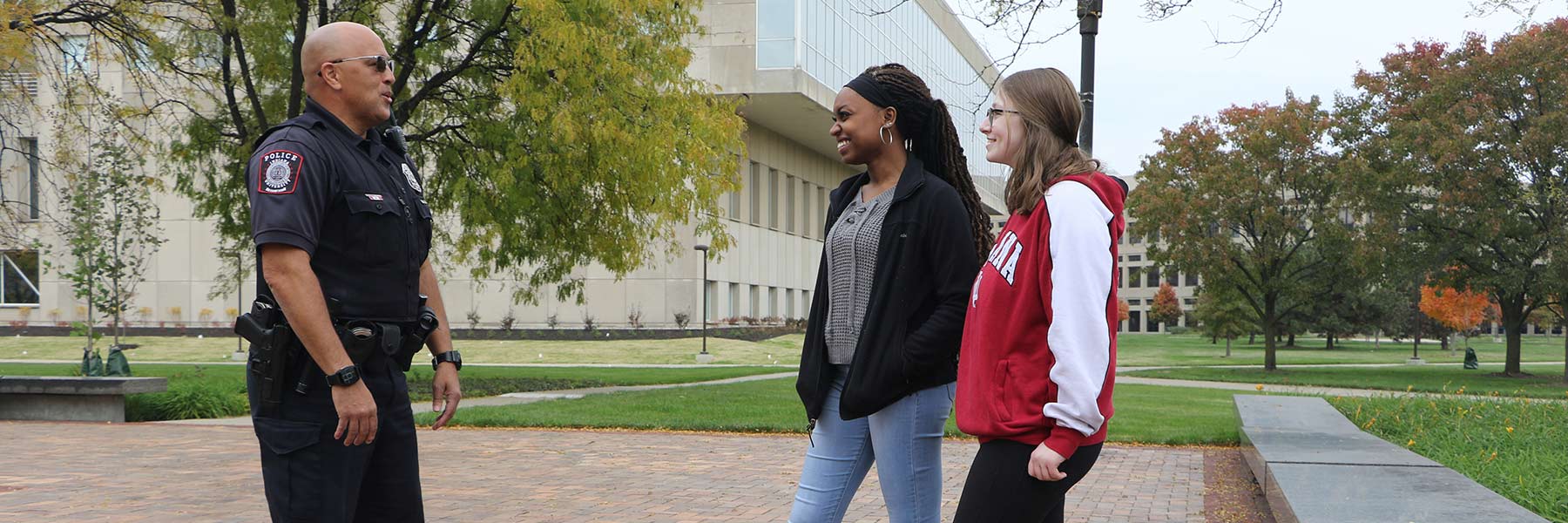 A male officer speaks at a distance with two young students on the IUPUI campus.